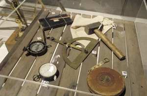 Old fashioned surveying instruments including a hammer, compass, notebook and tape measure