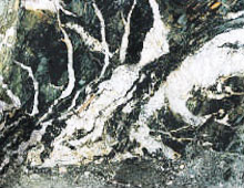 A black rock face showing veins of white rock spreading through in thing tendrils