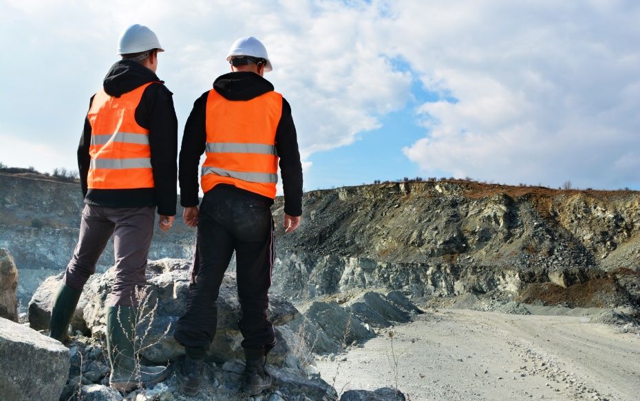 Two men in high vis looking over a mine or quarry