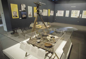 A case in a museum room with old fashioned surveying instruments sitting on display